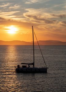 Sailing at sunset, Boat on calm sea and orange sky background,