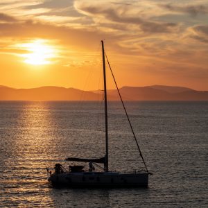 Sailing at sunset, Boat on calm sea and orange sky background,