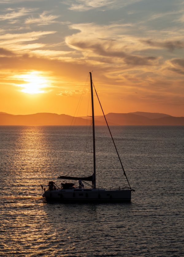 Sailing at sunset, Boat on calm sea and orange sky background,